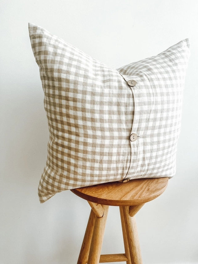Checkered pillow on a wooden stool against a white background