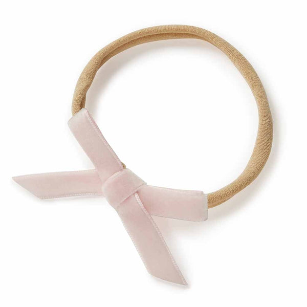 Beige headband with a pink velvet bow on a white background
