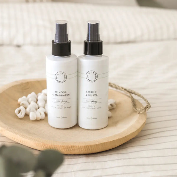 Two white spray bottles with black caps on a wooden tray.