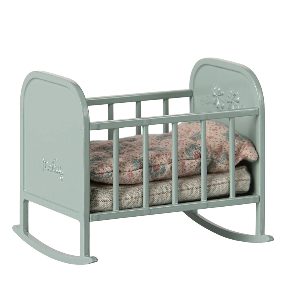 Light blue baby crib with floral bedding on a white background