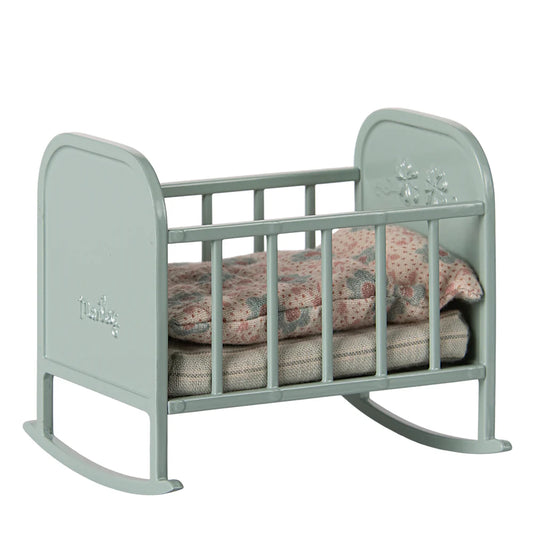 Light blue baby crib with floral bedding on a white background