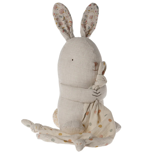 Stuffed rabbit toy with floral ears and a patterned blanket on a white background