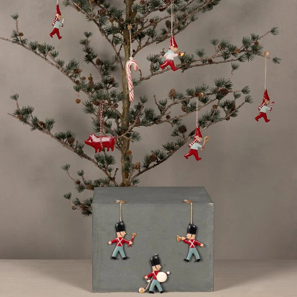 Decorative Christmas tree with ornaments including gnomes, pigs, and soldiers on a plain background.