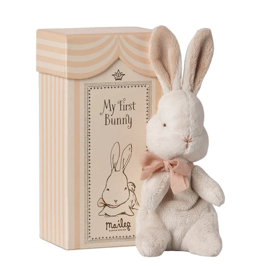 Plush bunny toy with a pink bow in front of a branded box on a white background