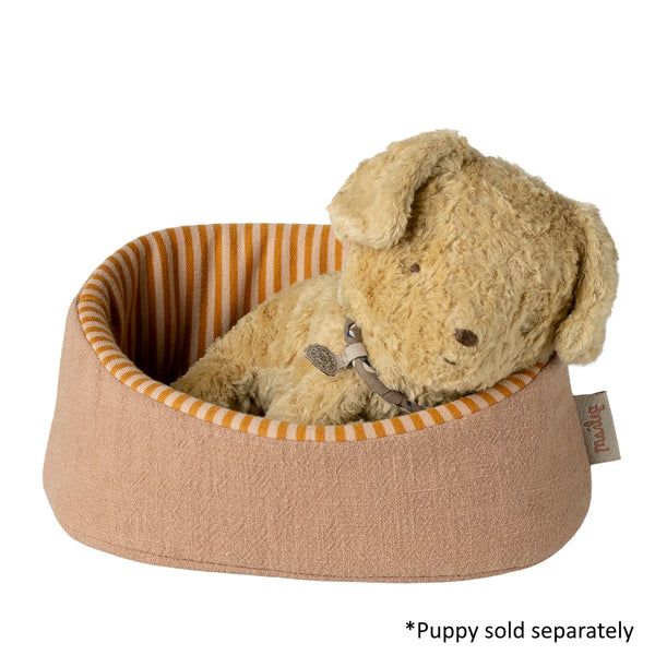 Dog bed with a plush dog toy inside on a white background