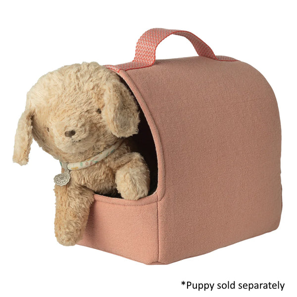Pink pet carrier with a toy dog inside on a white background