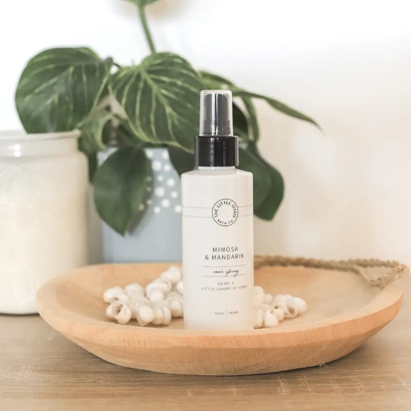 White bottle with black cap on a wooden plate with green leaves in the background