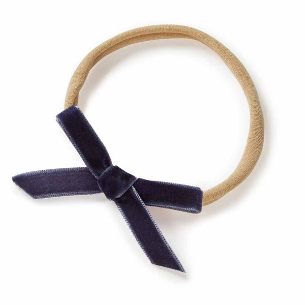 Navy blue velvet bow on a beige headband against a white background