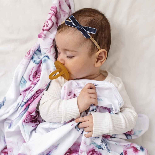Baby with a pacifier and floral blanket