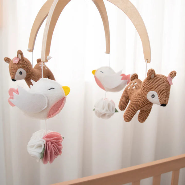 Baby mobile with deer, bird, and flower plush toys hanging from a wooden arch.