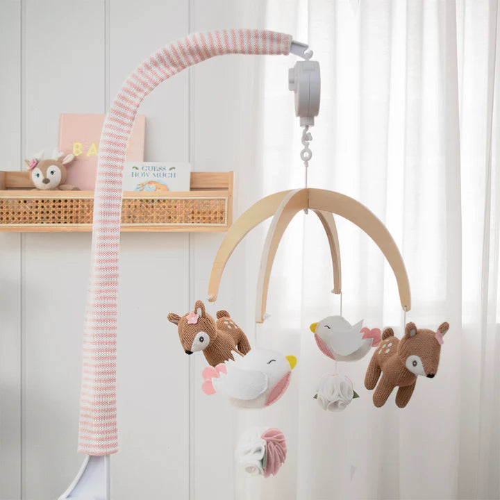 Wooden baby mobile with plush animals hanging against a white wall.