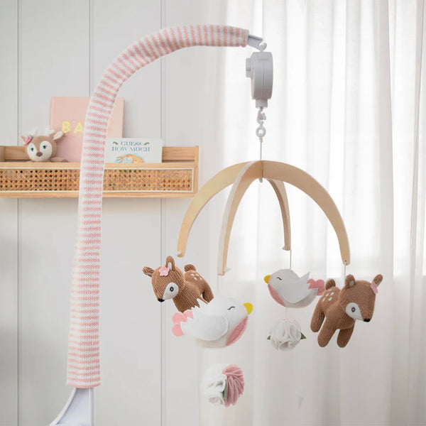 Wooden baby mobile with plush animals hanging against a white wall.