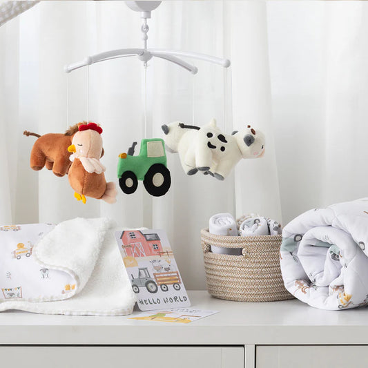Baby mobile with plush toys and nursery items on a dresser.