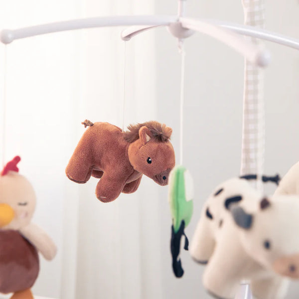 Plush animal toys hanging from a crib mobile against a white background