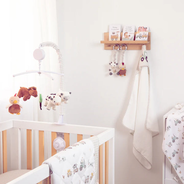 Nursery room with crib, toys, and hanging items on a white wall.
