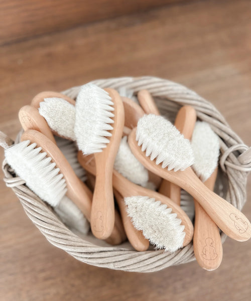 Basket of wooden baby brushes with soft bristles on a wooden surface