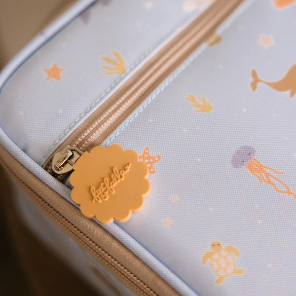 Close-up of a product with a zipper and sea-themed design on a light blue background.