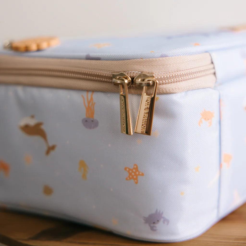 Light blue pouch with gold zipper and sea-themed pattern on a wooden surface