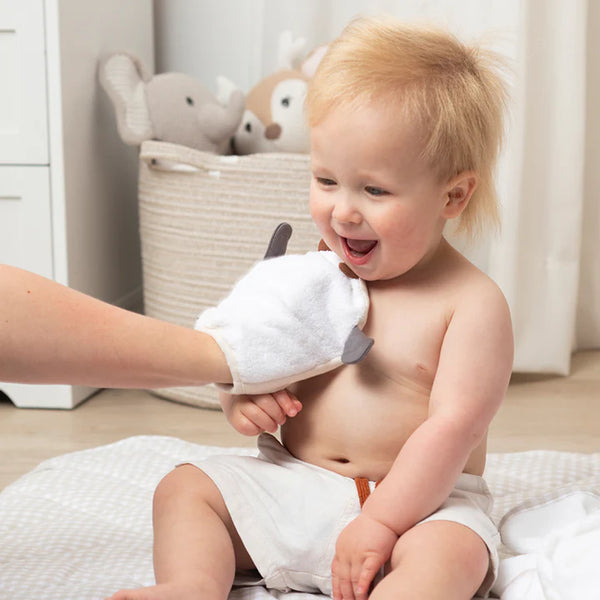 Child being bathed with a plush toy in a bathroom setting