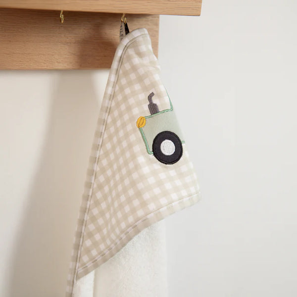 Checkered towel with a cartoon character hanging on a wooden rod against a white wall.