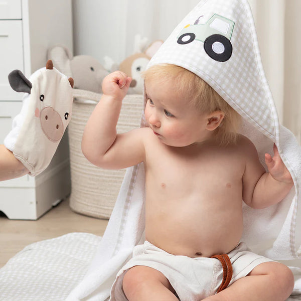 Baby wearing a hooded towel with a car design, surrounded by baby toys.