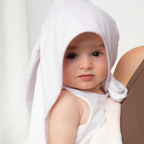 Baby wrapped in a towel with a hood, sitting on a white background