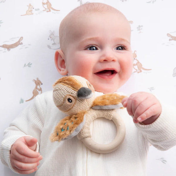 Baby holding a plush toy with a white background featuring animal prints