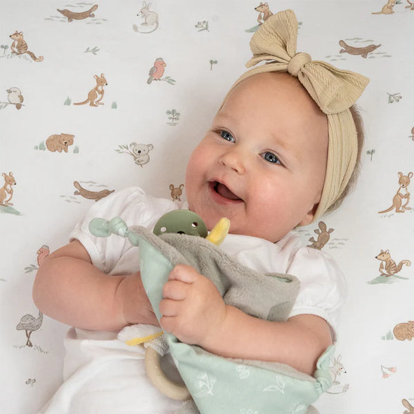 Baby holding a soft toy with a patterned background