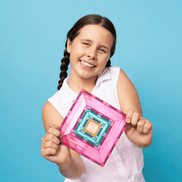 Young girl holding a pink and blue geometric shape against a blue background