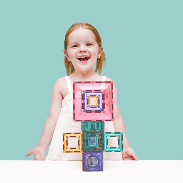 Child holding colorful geometric blocks against a light blue background