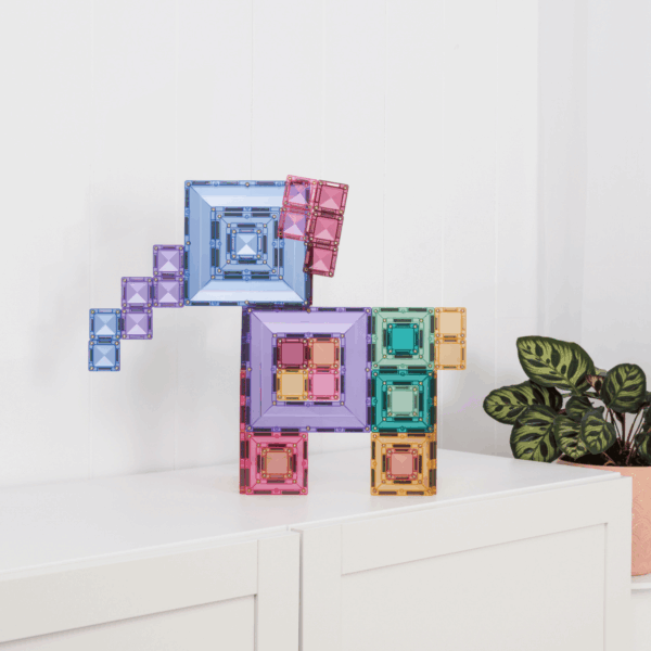 Colorful geometric wall art on a white wall with a plant in the corner.