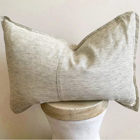 Striped pillow on a stool with a plain background