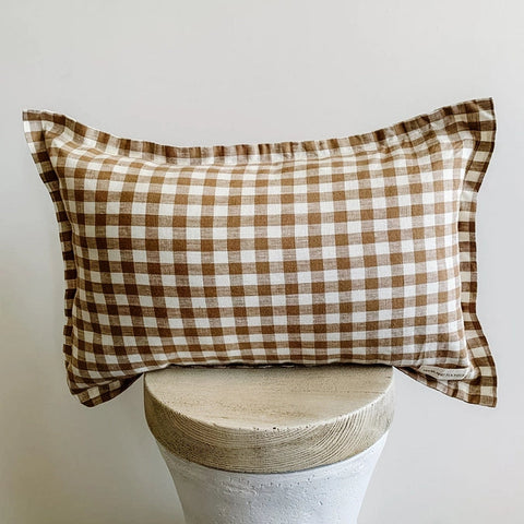Checkered pillow on a stool against a plain background