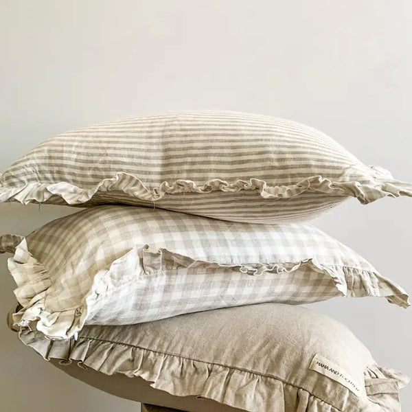 Three striped pillows with ruffled edges stacked on a white surface.