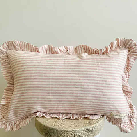 Pink striped pillow with ruffled edges on a light gray background