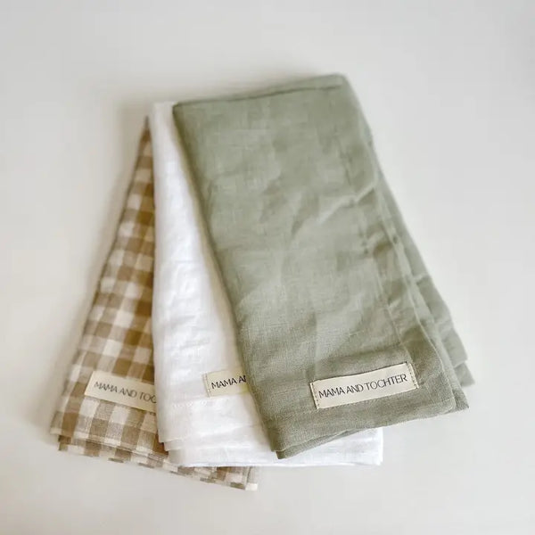 Three folded towels with 'Mama and Co.' labels on a light background
