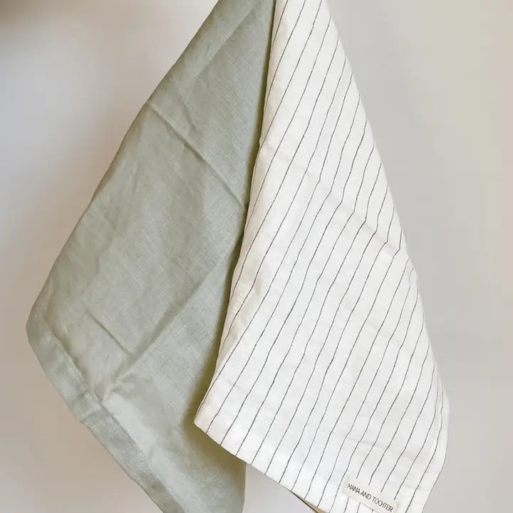 Light green fabric draped over a white surface with a notebook underneath
