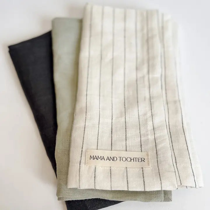 Three folded fabric towels with a visible brand label on a white background