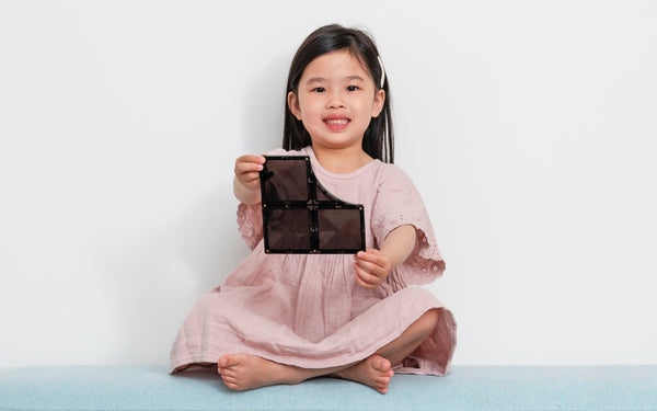 Young girl holding a black rectangular CONNETIX TILE Against a white background