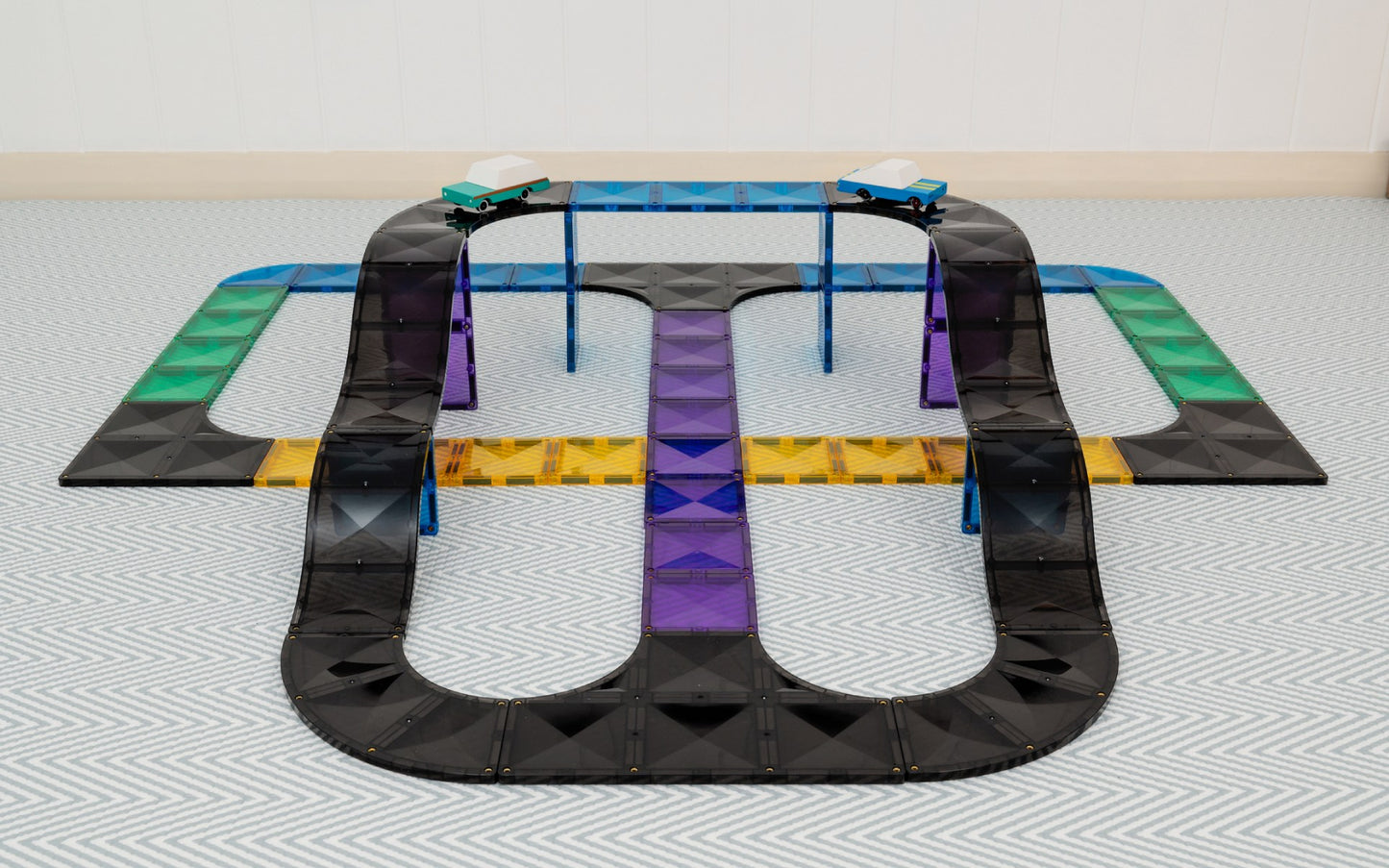 Black toy track with colorful sections on a light gray floor.
