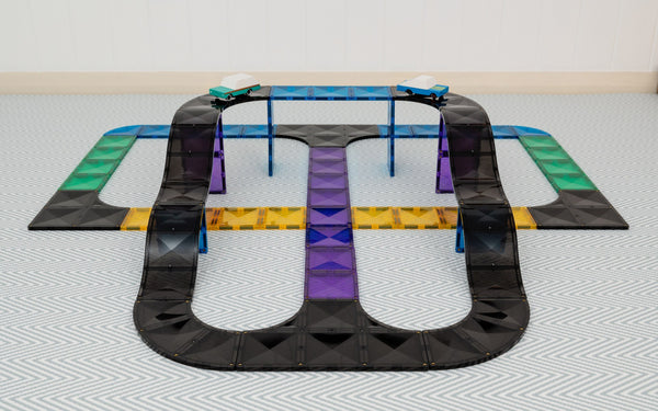Black toy track with colorful sections on a light gray floor.