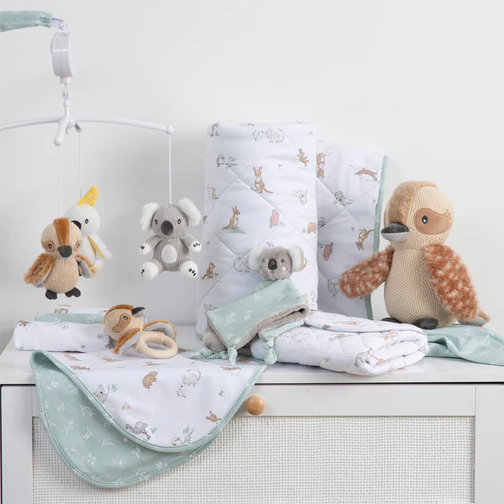Baby crib with crib mobile, blankets, and stuffed animals on a white background