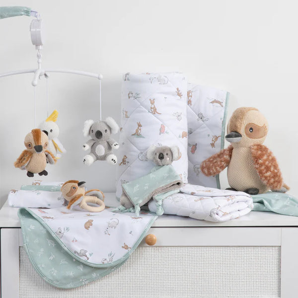 Baby crib with crib mobile, blankets, and stuffed animals on a white background
