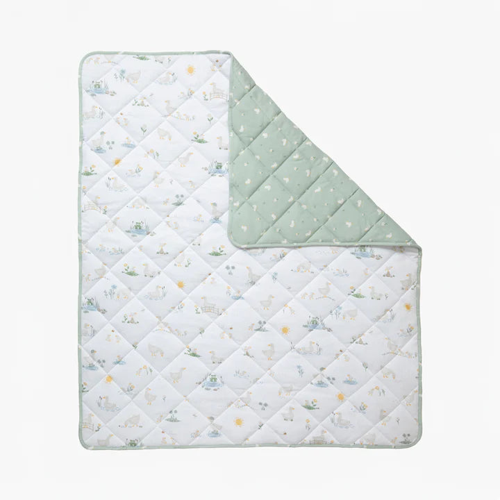 Quilted baby blanket with animal pattern on one side and solid color on the other, on a white background.