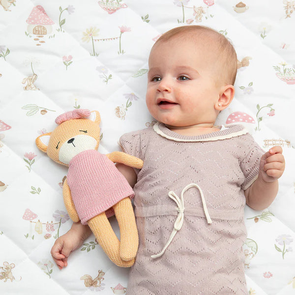 Baby lying on a patterned blanket with a fox-shaped toy
