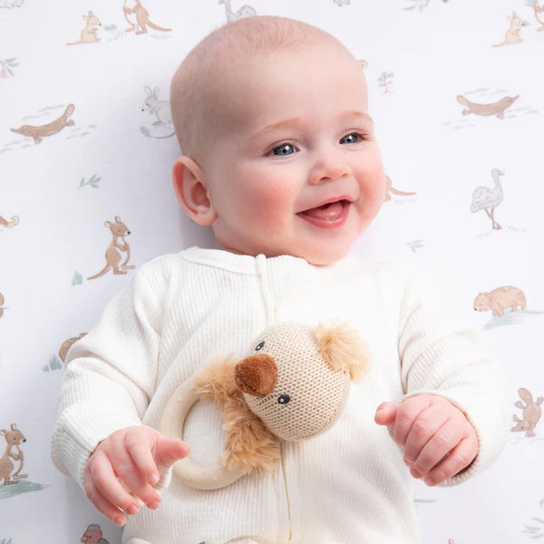 Baby holding a knitted toy with a patterned background