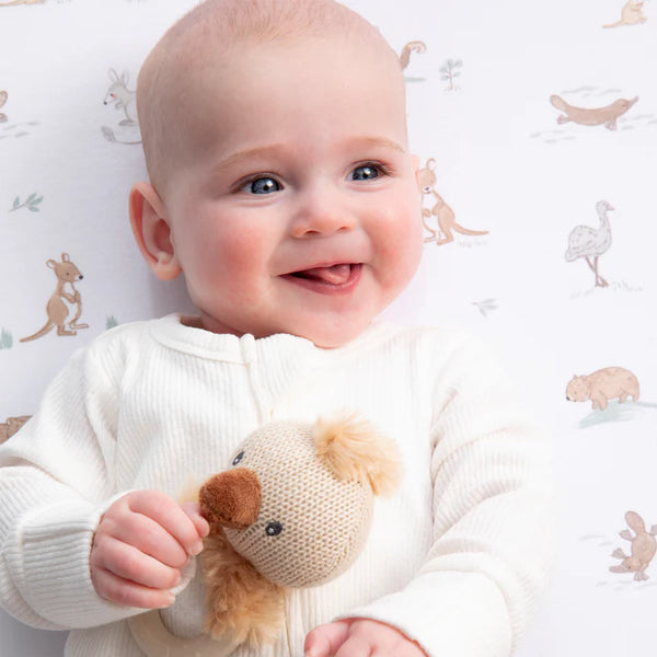 Baby holding a knitted toy with a patterned background