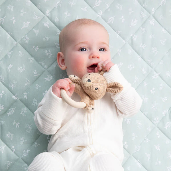 Baby holding a plush toy on a quilted surface