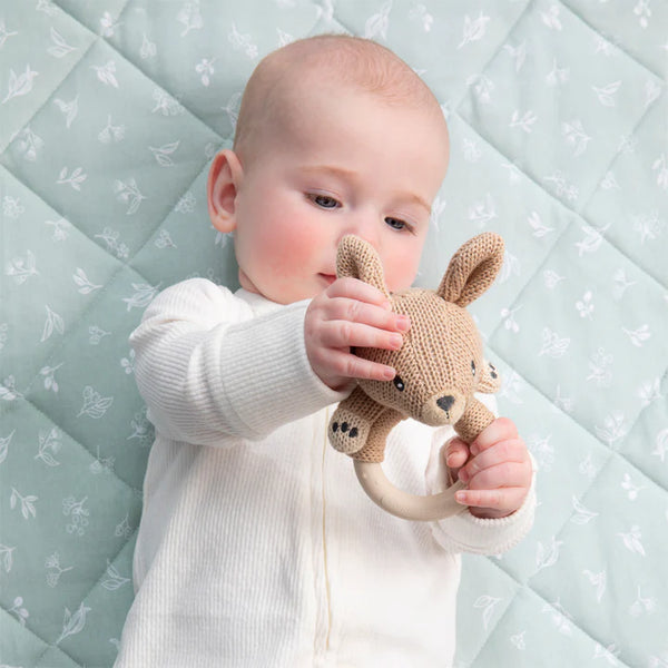 Baby holding a knitted toy against a patterned background