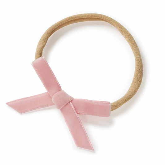 Beige headband with a pink velvet bow on a white background